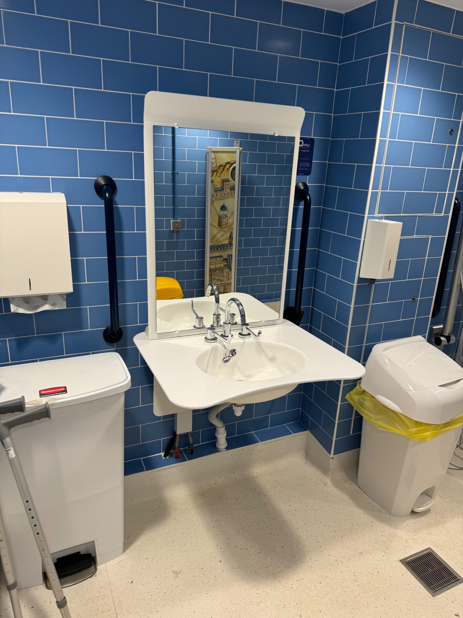 Height adjustable sink paper towel to the left above the bin and mirror