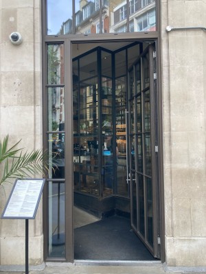 Open via glass door with metal frame. Push open via vertical handrail on left.