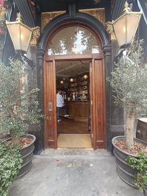 Glass door with brown frame. Golden pad on right. Push to open.