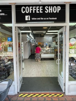 Facing venue. Glass doors with white frame ahead. Push open via handles in center.
