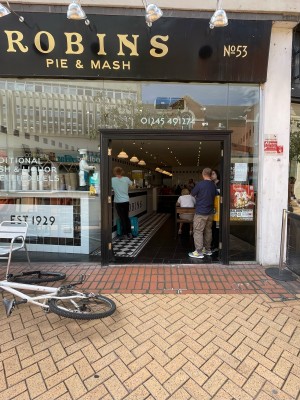 Facing entrance. Dark grey wood-framed glass doors ahead. Glass walls either side. No handles. Push centre to open.
