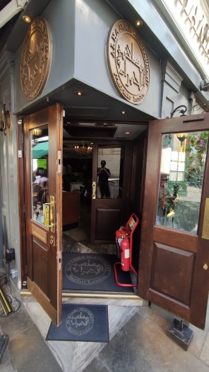 Double glass doors with brown wooden frames. Pull gold metal handles in centre to open.
