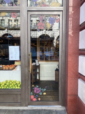 Access via glass door with brown frame. Push open via vertical metal handle on left.