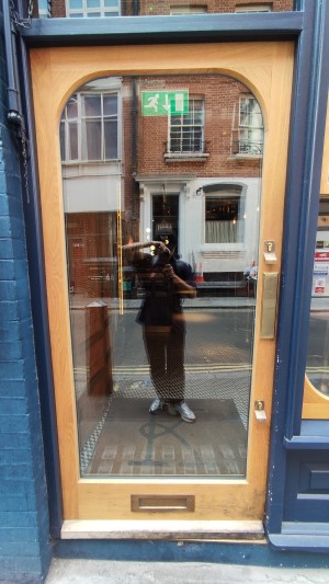 Single glass door in brown and blue wooden frames. Push gold metal panel from right to open.