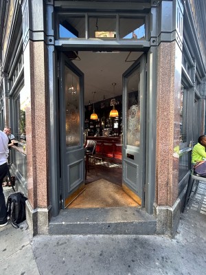 Double dark grey wooden doors with large glass panels. Push vertical gold metal handles in middle to open.