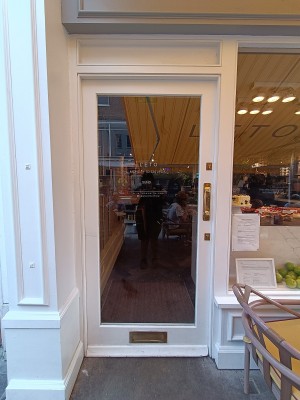 Glass door with white frame. Golden handle on right. Push to open.