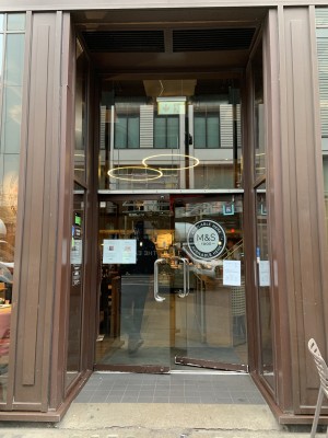 Facing entrance door. Built-in ramp ahead to glass door. Push silver metal handles in centre of door to open.