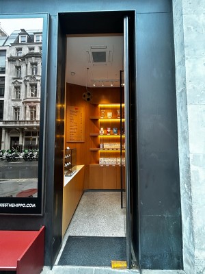 Single glass door with silver handle on mid right. Push to open.