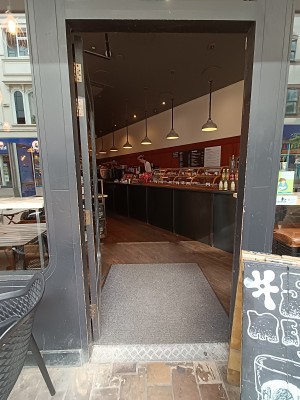 Single glass door with black wooden frame. Push brass handle on right to open.