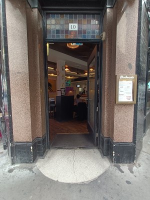 Single glass door with black wooden frame. Push silver metal doorknob on left to open.