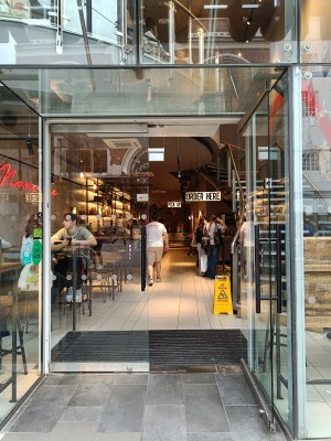 Glass door with black vertical handles in the middle. Pull to open.