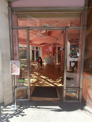Glass door with brown vertical handle on left. Push to open.