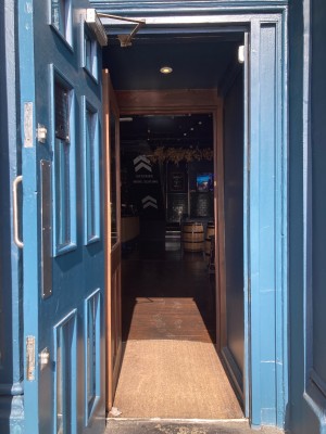 Access via wooden blue door with glass panels. Open via metal handle on right.