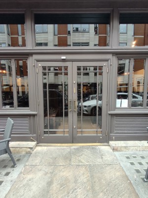 Facing grey framed double glass doors. Pull golden metal handles in centre to open.