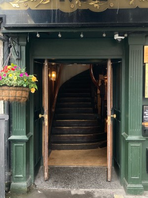 Access via double wooden doors with glass panels. Pull open via metal handles in center.