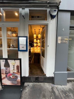 Single glass door in white wooden frame. Push gold metal handle from left to open. Menu sign left.