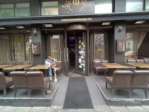 From street, facing venue. Seating on both sides. Doorway at back. Path in middle.