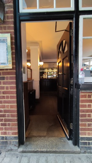 Single black door ahead. Push golden metal knob in centre to open.