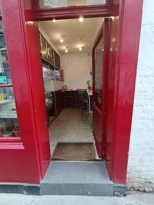 Glass door with red frame. Golden handle on left. Push to open.