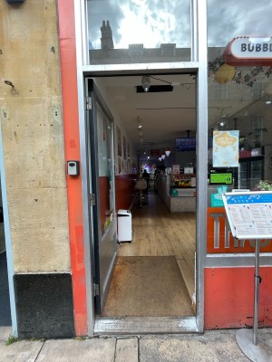 Single glass door in silver metal frame. Push silver metal handle from right to open. Menu sign right.