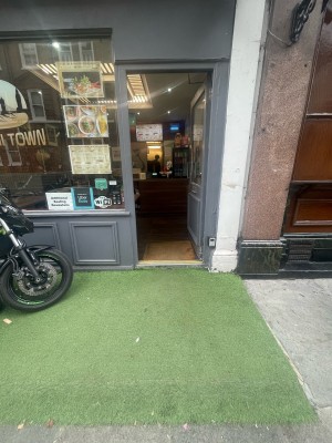 From street, facing straight. Grass path with a raised edge ahead. Entrance door ahead of it.