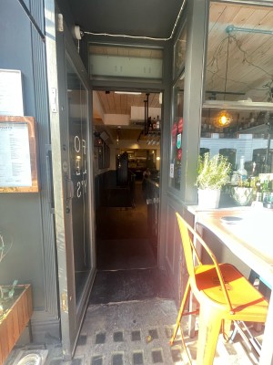 Glass door with wooden frame ahead. Vertical metal handle to right. Pull to open.