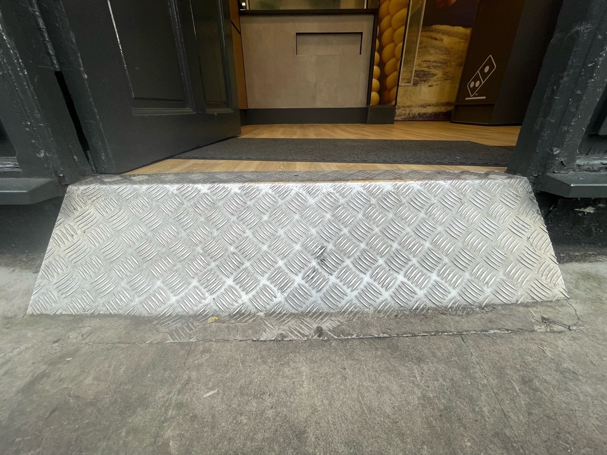 Steep step at foot of door, followed by doormat.