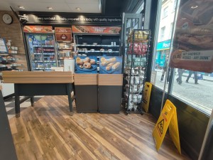 From entrance facing right. Path ahead going left to counter. Display shelves along back.