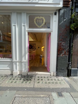 Pink wood-panelled glass doors ahead. One stone step before doorway. No handles. Push doors at centre to open.