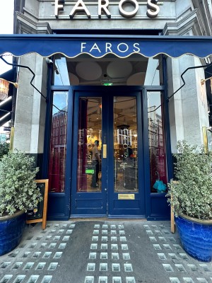 Blue and glass panelled doors. Gold pad to top right of left-hand door, push to open. Purple curtains beyond.