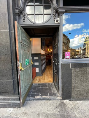 From sidewalk to left of main entrance facing venue. Wooden door ahead. Pull on right to open or ask staff to unlock.