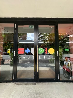 Glass doors with black frames. Gold vertical handles in centre. Pull to open.
