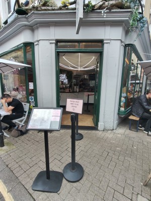 Facing entrance. Waiting queue dividers ahead. Path on both sides of divider to door at back.