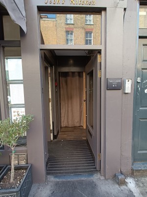 Glass door with brown frame. Metal, golden knob on left. Push to open.