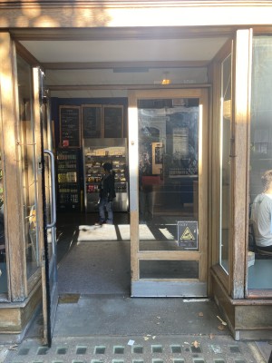 Access via double glass door with wooden frame. Push open via metal pads in center.