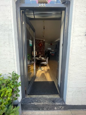 Glass door with grey frame ahead. Metal handle to right. Push to open.