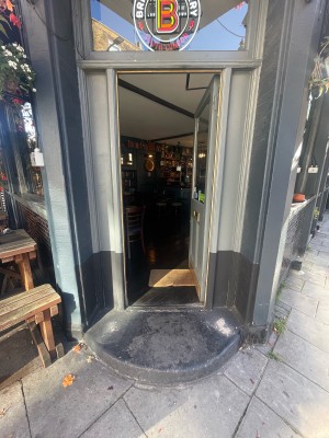 Wooden and glass grey door ahead. Gold panel to left. Push to open.