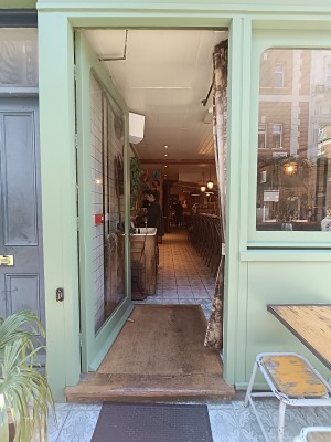 Glass door with green frame. Golden metal handle on right. Push to open.