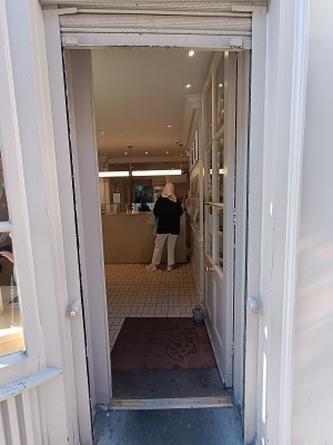 Glass door with white frame. Silver metal pad on left. Push to open.