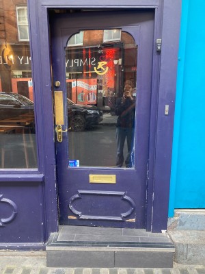 Access via wooden purple door with glass panel. Push open via handle and metal pd on left.