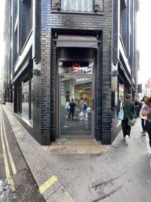 Metal-framed glass door ahead. Textured surface at threshold of door. Pull black metal handle on right to open.
