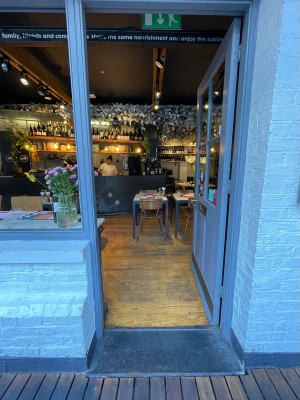 Wood-framed glass door ahead. White walls on left and right. Open window frame along left.