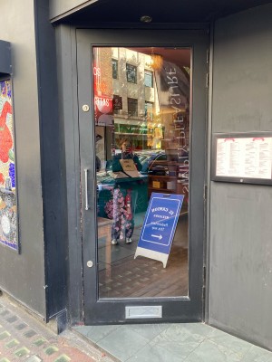Access via glass door with black frame. Push open via metal handle on left.