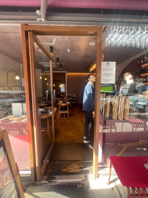 Glass door with wooden frame ahead. Metal handle to right. Push to open.