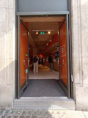 Glass doors with curved, silver, metal handles in middle. Push to open. White doorbell on right doorframe.