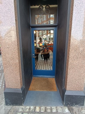Glass door with blue frame. Golden metal handle on left. Push to open.