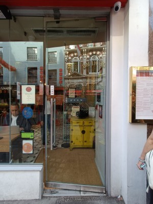 Glass door with silver, metal vertical handle on left. Push to open.