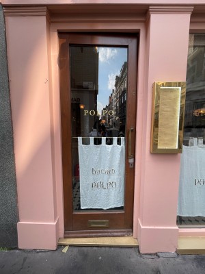 Glass door with brown frame ahead. Vertical metal handle to right. Push to open.