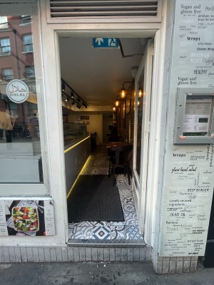 Glass door with white frame ahead. Hold metal vertical handle to left. Push to open.
