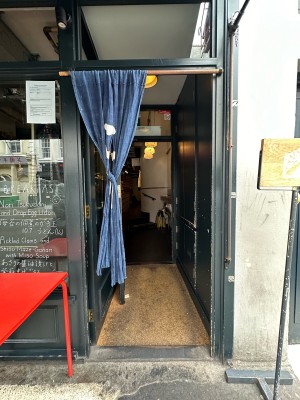 Open archway ahead with Blue half curtain. Slide curtain open from right. Standing sign to right of archway, table to left.